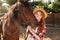 Cheerful woman cowgirl in hat with her horse in village