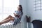 Cheerful woman delighting in book and drinking coffee on window sill