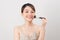 Cheerful woman is doing make up on her face using brush. Beauty routine on white background