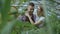 Cheerful woman embrace and kiss husband watering flowers with garden pot. Happy young florist couple in apron working in