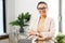 Cheerful woman entrepreneur stands with arms crossed in the contemporary office