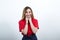 Cheerful woman in fashion red shirt smiling, keeping fingers on cheeks