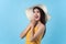 Cheerful woman glad emotion in yellow dress and summer hat isolated on light blue background in studio