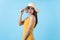 Cheerful woman glad emotion in yellow dress and summer hat isolated on light blue background in studio