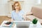 Cheerful woman holding a cup of tea while working