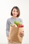 Cheerful woman holding a shopping bag full of groceries