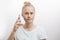 Cheerful woman holding smartphone and looking at camera over white background