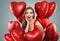 Cheerful woman holds red balloons. Surprised model girl with red lips makeup, perfect curly hairstyle and cute smile. Birthday