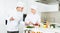 Cheerful woman and man young chefs preparing food with paper recipe