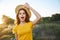 Cheerful woman with open mouth holds hand on hat nature vacation photographer