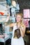 Cheerful woman picking earrings in jewellery boutique