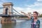 Cheerful woman pointing to Chain Bridge at Budapest, Hungary