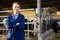 Cheerful woman posing in cowshed on farm breeding dairy cows