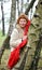 The cheerful woman with a red scarf costs having leaned against a birch in the wood