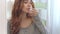 Cheerful woman rinsing mouth with oral rinse from bottle front bathroom mirror