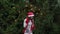 Cheerful woman in Santa hat with red scarf and mittens is happy and dancing on a background of Christmas tree in