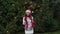 Cheerful woman in Santa hat with red scarf and mittens is happy and dancing on a background of Christmas tree in