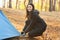 Cheerful woman setting up tent, forest background