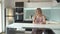 Cheerful woman sitting at the table in the kitchen