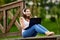 Cheerful woman in wireless headphones makes telework with laptop outdoors.