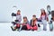 Cheerful women friends in sports winter clothes with snowboards and skis hugging together