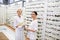 Cheerful workers of optical store standing near shelves with glasses