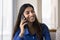 Cheerful young adult Indian girl speaking on mobile phone