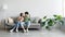 Cheerful young Asian couple sitting on sofa with credit card and cellphone, shopping online in living room, copy space