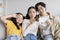 Cheerful young asian guy hugs wife, lady makes blowing kiss, teen daughter makes peace sign and take photo