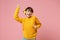 Cheerful young brunette woman girl in yellow sweater posing isolated on pastel pink wall background studio portait