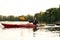 Cheerful young caucasian guy smiling while boating together with his friends on a lake surrounded by peaceful nature