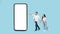 Cheerful young caucasian husband hold hand of arab wife, point finger at huge smartphone with empty space