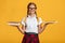 Cheerful young caucasian schoolgirl with pigtails, backpack in glasses hold book and tablet and chooses