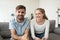 Cheerful young couple bloggers looking laughing at camera at home