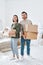 Cheerful young couple in casualwear holding carton boxes with packed stuff
