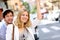 Cheerful young couple waving for taxi in town