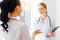 Cheerful young doctor listening to colleague at hospital