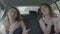 Cheerful young female best friends singing and dancing in the car on road trip celebrating freedom and having fun -