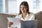 Cheerful young freelance employee woman reading document at laptop