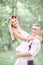 Cheerful young groom closes his eyes while raising blonde bride