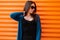 Cheerful young hipster woman in vintage long knitted cloak in a stylish black top in black jeans in vintage sunglasses posing