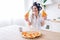 Cheerful young housewife in kitchen holding two slices of pizza. Smiling. Curlers in hair. Lifestyle without work