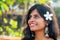 Cheerful young indian woman with white flover in hair relaxing on beach in Goa