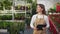 Cheerful, young lady wearing uniform, walking, working in greenhouse.