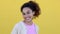 Cheerful young Latin American woman smiling at camera over yellow background.