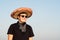 Cheerful young male person in sombrero in clear sky background.