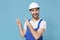 Cheerful young man in coveralls protective helmet hardhat isolated on blue wall background. Instruments accessories for