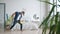 Cheerful young man dancing singing washing floor in apartment with plastic mop