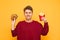 Cheerful young man holds french fries and a burger in his hands, looking into the camera, isolated on a yellow background. Happy