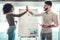 Cheerful young man and woman giving high-five near white marker board in creative office